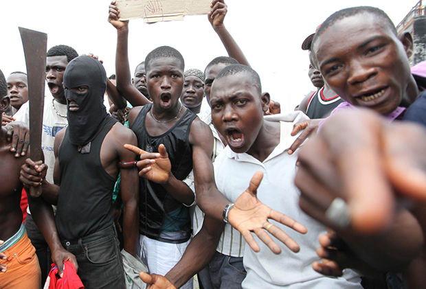 Masked anti-Gbagbo protester holds a machete during protests in the Abobo area of Abidjan